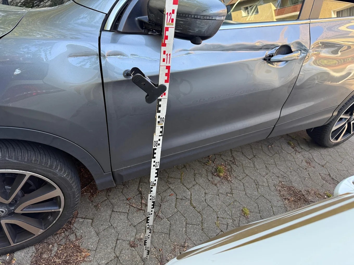 Schadendokumentation mit Messlatte an einem Fahrzeug